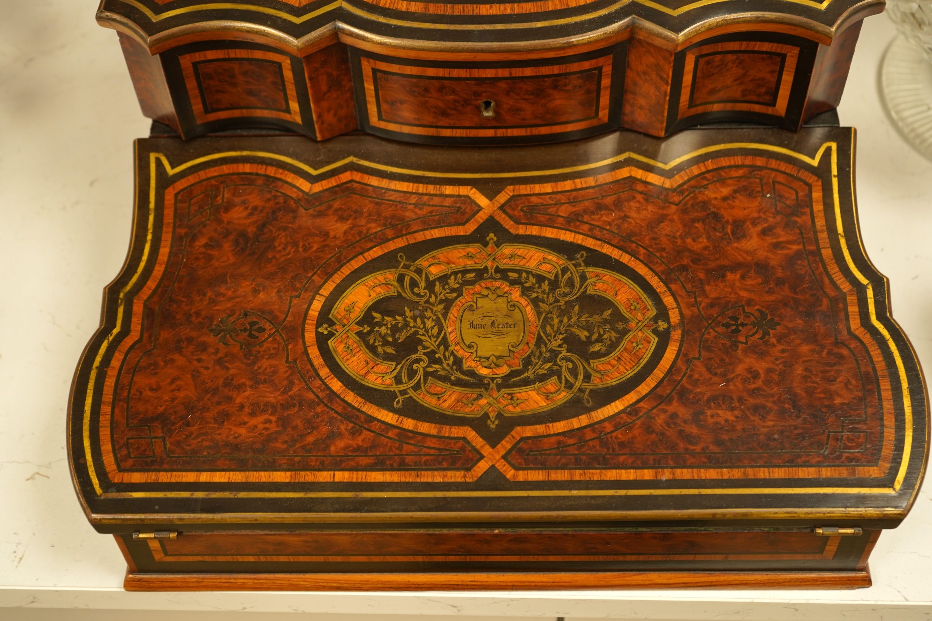 A 19th century French brass inlaid, tulip banded amboyna writing casket, the brass panel inscribed ‘Jane Lester’, 40cm wide